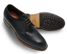 Black leather dress shoe with brown sole on a white background