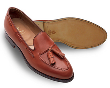 Brown leather loafer shoe with tassels on a white background