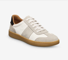 White sneaker with brown sole on a light gray background