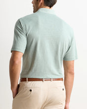 back side of man in willow green polo and khaki pants.