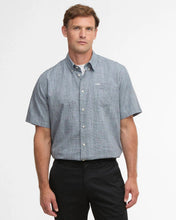 Man wearing a blue checkered shirt and black pants on a white background