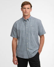 Man wearing a blue checkered short-sleeve shirt on a light gray background