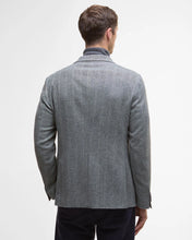 Man wearing a gray blazer from behind on a light gray background