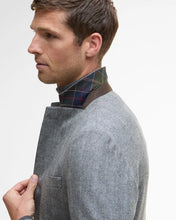 Man wearing a gray sweater with a plaid collar against a white background