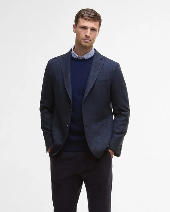 Man wearing a dark suit with a white shirt on a light gray background