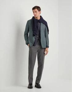 Man wearing a green blazer, gray pants, and a dark scarf on a white background