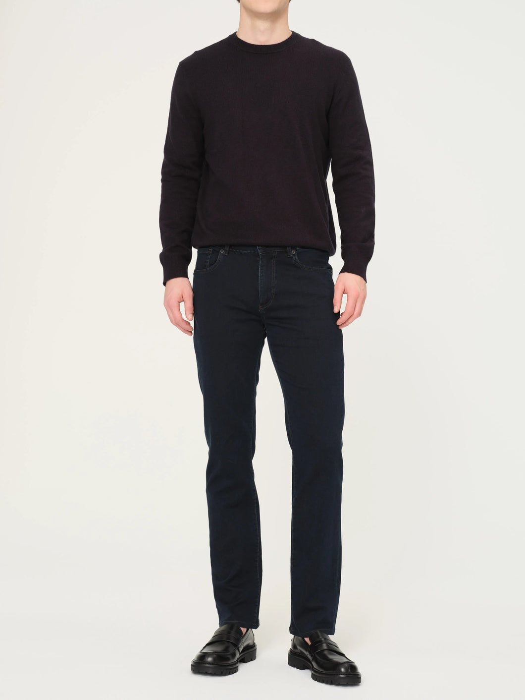 Person wearing a black sweater and black jeans on a white background