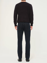 Person wearing a black sweater and dark jeans on a white background