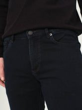 Dark jeans worn by a person on a light background