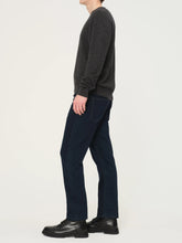 Person wearing a dark gray sweater and navy pants on a white background