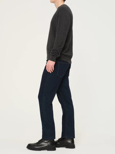 Person wearing a dark gray sweater and navy pants on a white background