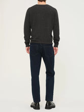 Person wearing a dark gray sweater and blue jeans on a white background