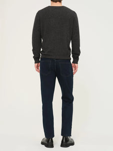 Person wearing a dark gray sweater and blue jeans on a white background