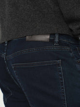 Dark blue jeans with a visible brand label on the back pocket, worn by a person wearing a dark sweater.