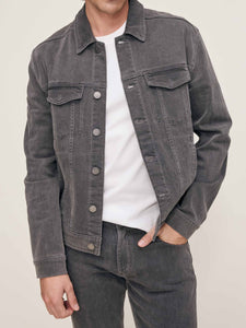Person wearing a gray denim jacket over a white shirt on a beige background