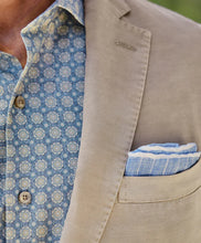 Close-up of a beige blazer with a blue patterned shirt and matching pocket square.