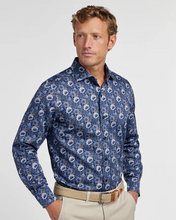 Man wearing a blue floral shirt and beige pants on a light gray background