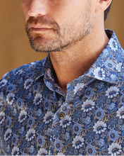 Man wearing a blue floral patterned shirt against a wooden background