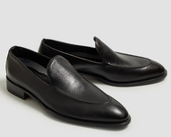 Pair of black leather loafers on a light gray background