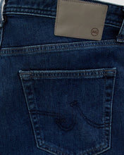 Close-up of blue jeans with a brand label on a light gray background