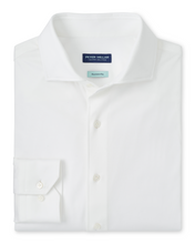 A folded white long-sleeve dress shirt with a spread collar and a single-button cuff, shown on a plain white background. The Peter Millar label is visible inside the collar.