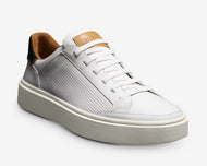 A white, low-top Allen Edmonds slip-on stretch-lace sneaker with perforated leather uppers and a tan sole.