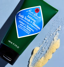 Green tube of Jack Black scalp scrub and shampoo with blue label on a light blue background