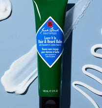 Green tube of Jack Black hair and beard balm on a light blue background