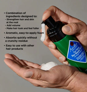 Hand holding a green bottle of hair product with text detailing its benefits on a gray background