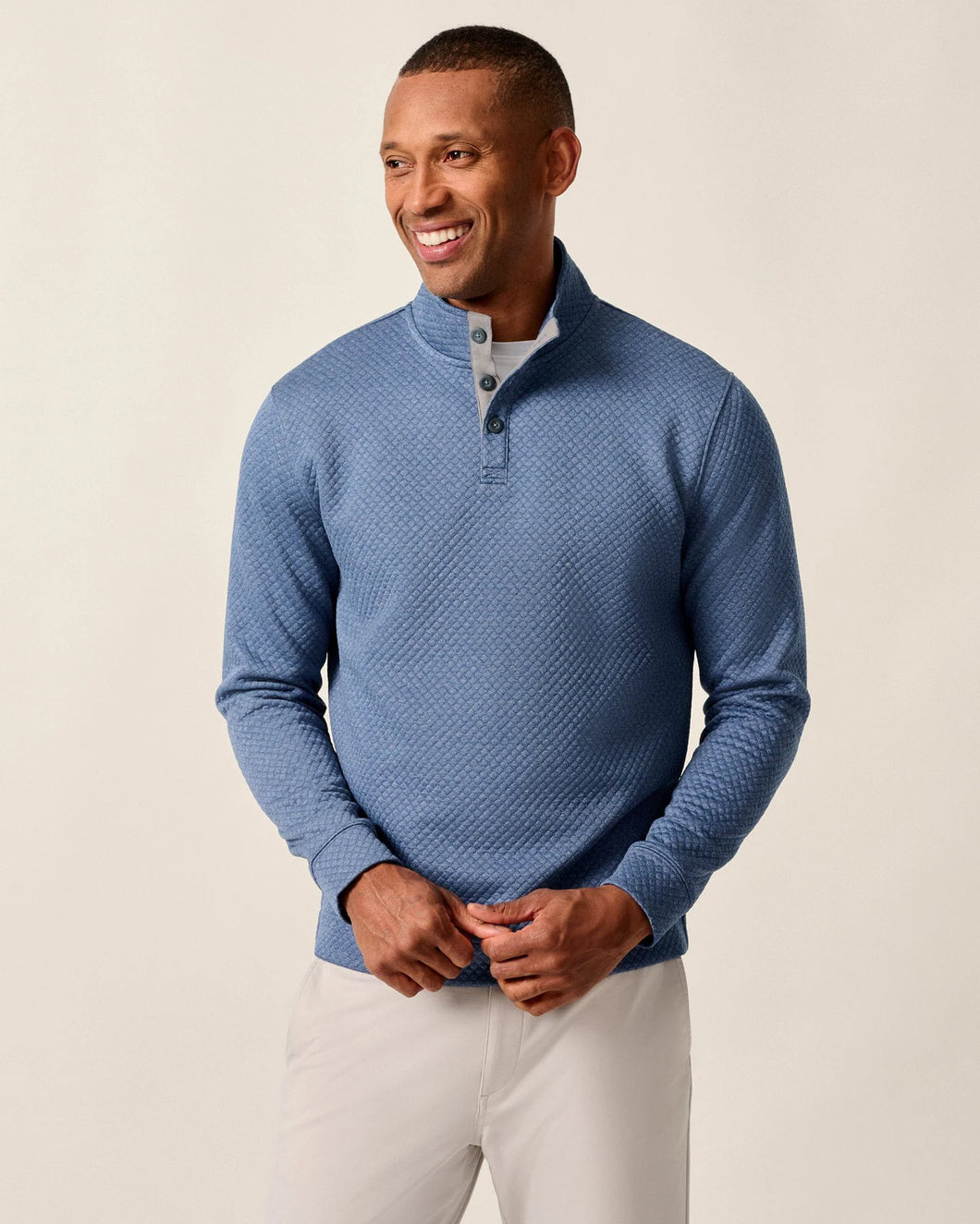 Man wearing a blue textured sweater against a beige background