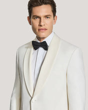 Man wearing a white tuxedo with a black bow tie on a light gray background
