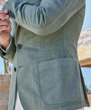 Close-up of a person wearing a green jacket with buttons and a pocket.