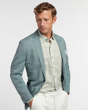 Man wearing a light blue blazer over a white shirt with a light gray background