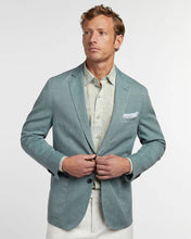 Man wearing a light blue blazer over a light shirt with a white background