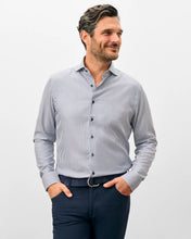Man wearing a gray striped shirt and navy pants on a light gray background