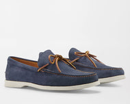 A navy blue Peter Millar boat shoe with a hand-stitched toe and brown leather laces.