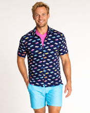 Man wearing a patterned shirt featuring Corvette cars and light blue shorts on a white background