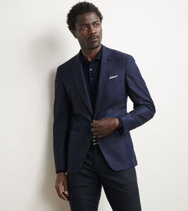 Man wearing a blue checkered blazer against a plain background