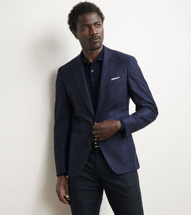Man wearing a blue checkered blazer against a plain background