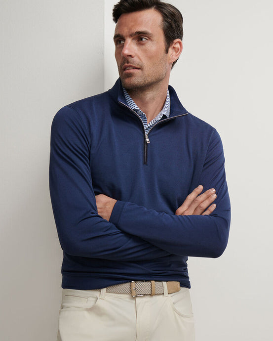 Man wearing a navy blue quarter-zip sweater with a light-colored background