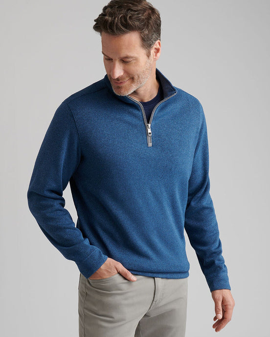 Man wearing a blue sweater with a zipper on a gray background