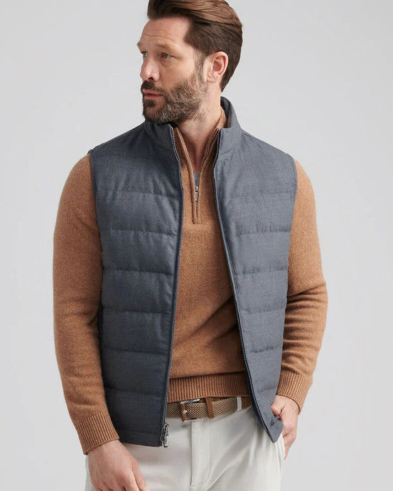 Man wearing a brown sweater and gray puffer vest on a light gray background