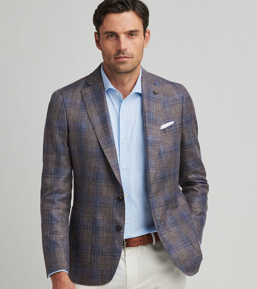 Man wearing a plaid blazer over a light blue shirt with a gray background