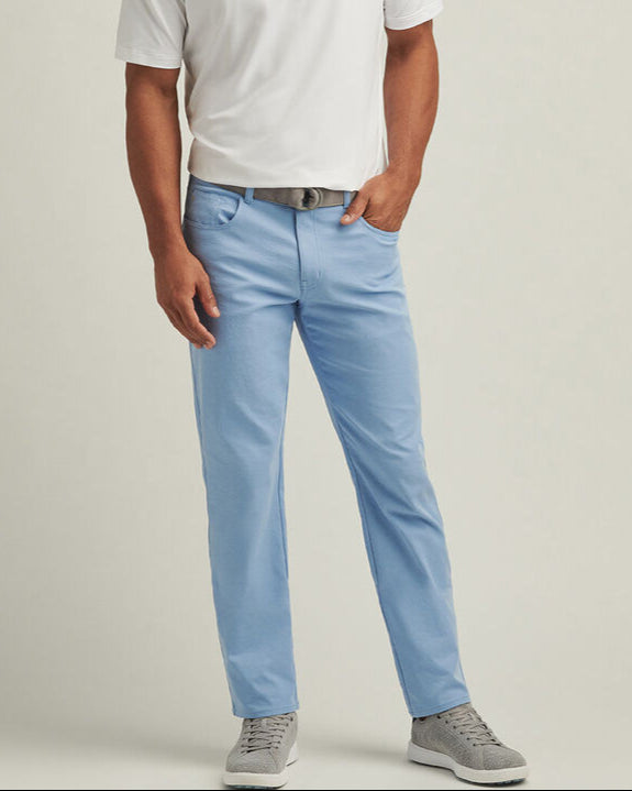 Man wearing a white polo shirt and light blue pants on a beige background