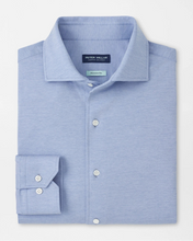 A light blue Peter Millar dress shirt folded neatly on a clean white background, featuring a classic collar, button-down front, and a double-button cuff.