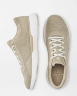 Pair of beige sneakers with white laces on a light gray background