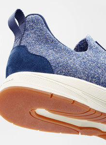 Blue slip-on sneaker with a white sole on a light gray background