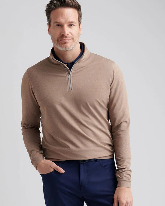 Man wearing a brown quarter-zip pullover and blue pants on a light gray background