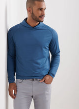 Man wearing a blue hoodie and gray pants against a white background