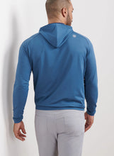 Man wearing a blue hoodie and gray pants against a white background